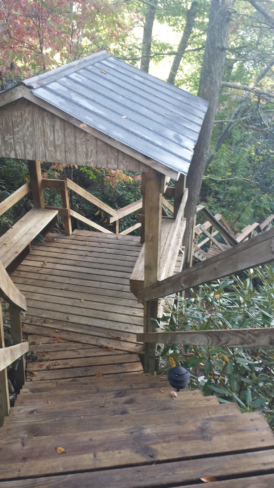 Metal roofed shelter over wooden steps on a wooded walkway — Skylight Repair & Installation work by our crew in Lawrence